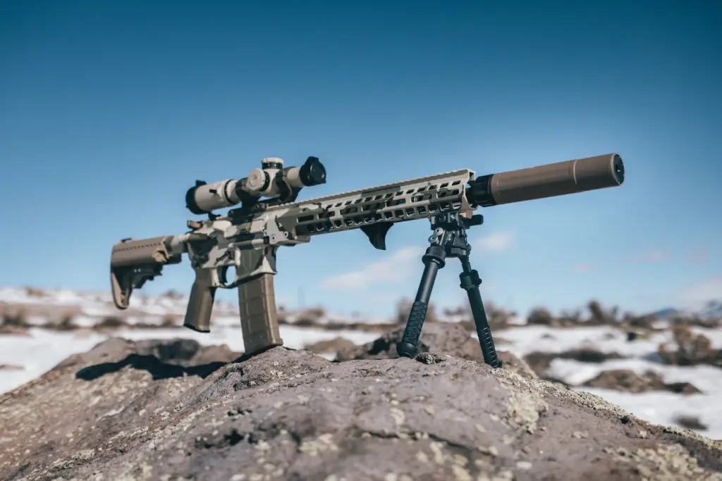 FDE AR carbine with suppressor standing on the Atlas PSR BT46-LW17 bipod on a snowy overlook